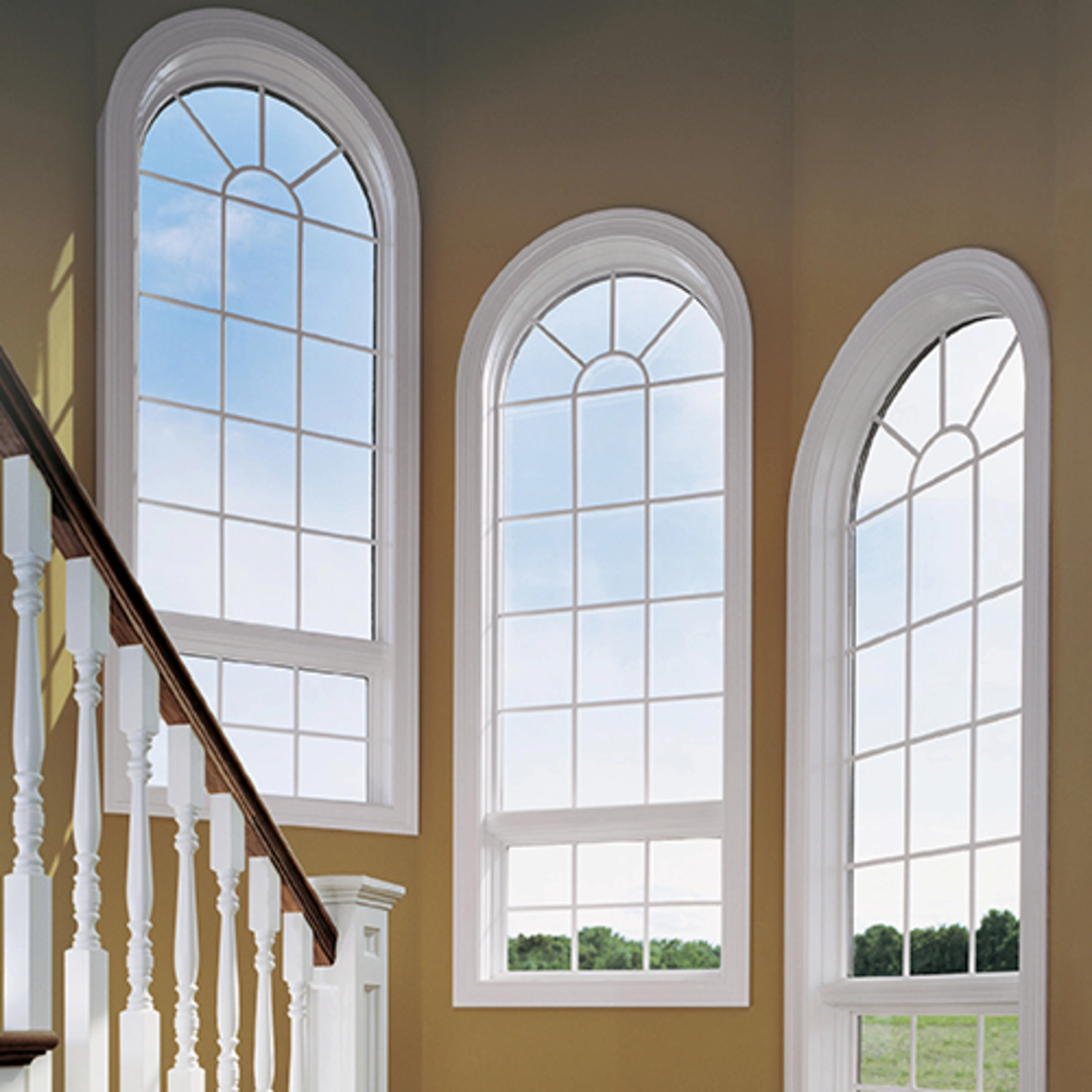 Tall arched replacement windows with white frames letting in natural light on a staircase, enhancing home style and energy efficiency
