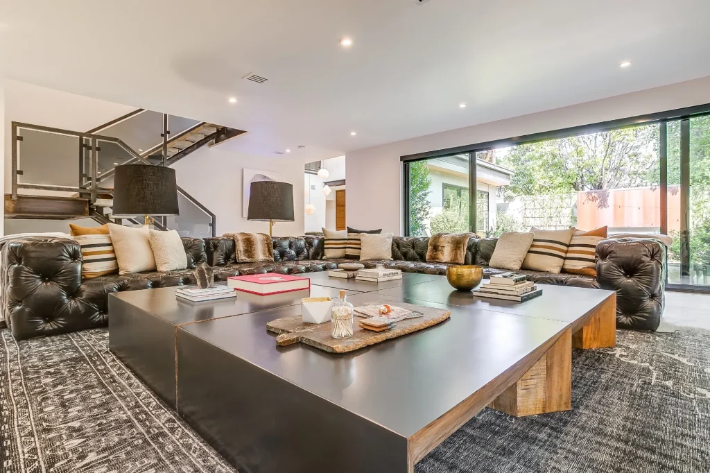 A stylish modern living room with large sliding openings framed by Quaker EdgeLine Windows, showcasing a seamless indoor–outdoor connection and contemporary design