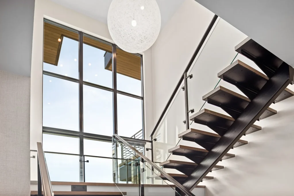 Modern stairway with large Quartz Luxury Windows bringing in natural light and showcasing clean, contemporary aluminum framing
