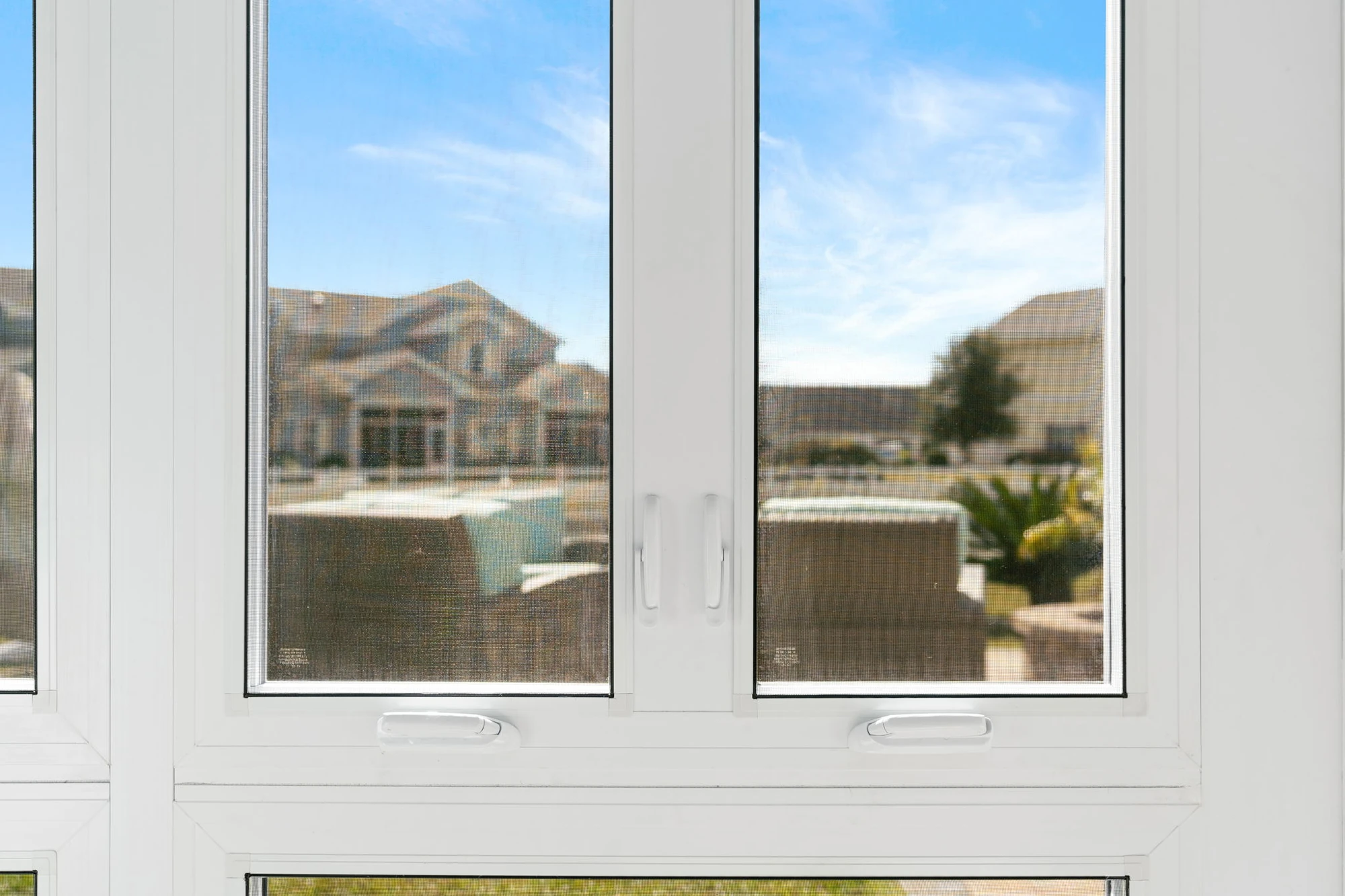 White sliding basement egress window with dual panes and secure hardware, overlooking an outdoor patio area