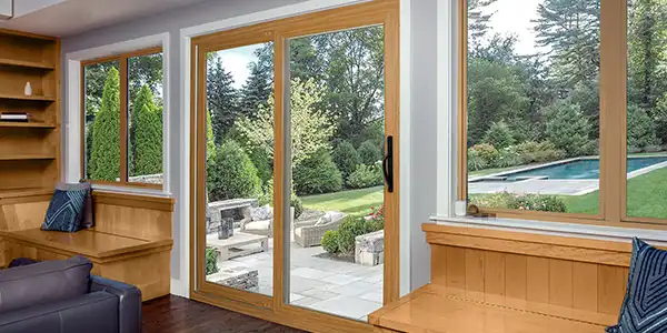 image of sliding vinyl patio doors with wood trim opening to a backyard and pool view