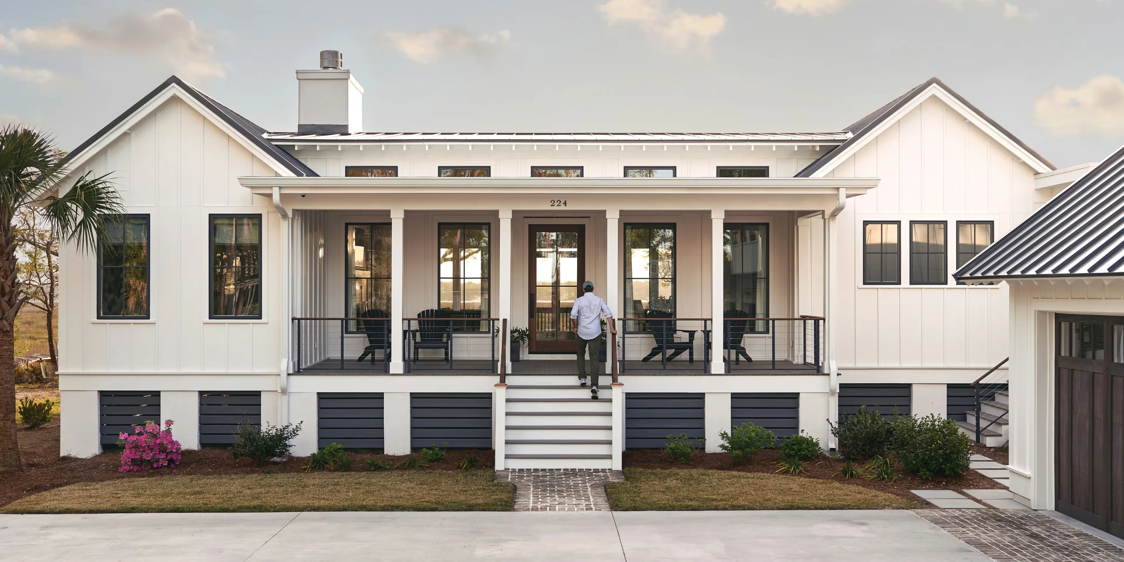 Image of a modern coastal farmhouse exterior with black Marvin window frames and a covered porch
