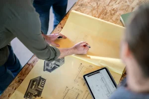Image of a contractor and homeowner reviewing blueprints to plan a window replacement project